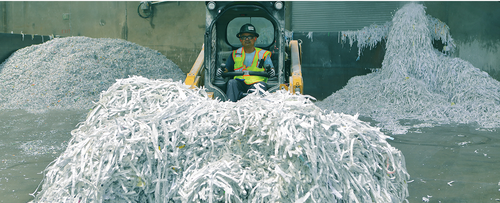 man in a forklift surrounded by piles of shredded paper