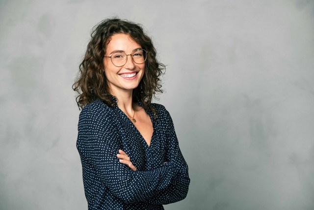 A woman smiles with arms crossed